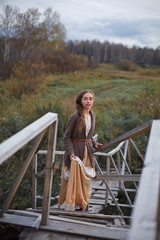 girl in vintage dress stands on a bridge