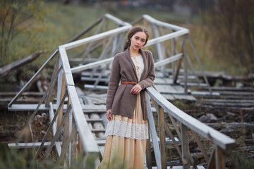 girl in vintage dress stands on a bridge