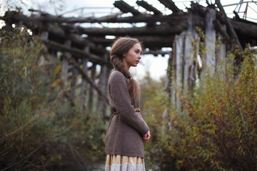 girl in vintage dress stands on a bridge