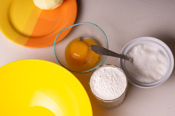 Ingredients for homemade pie stand on the table. Flour, sugar, chopped apples and egg. Close-up.