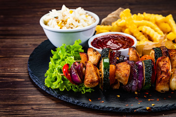 Grilled shashliks and French fries on black stone plate