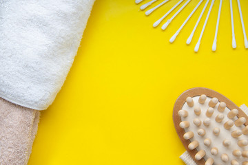 Bath accessories on a yellow background, cotton buds massage brush and towel