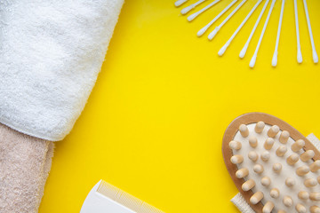 Bath accessories on a yellow background, cotton buds massage brush and towel
