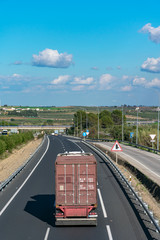 Container truck traveling on the highway with a blue sky with clouds