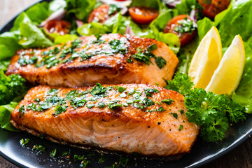 Fried salmon steaks with vegetables on wooden table