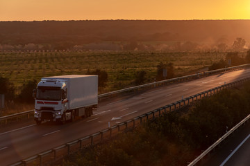 truck with refrigerated semi-trailer driving on the highway at sunset