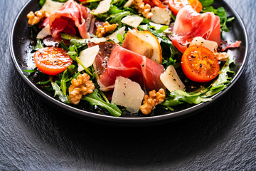 Tasty salad - ham and vegetables on black stone board