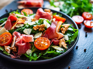 Tasty salad - ham and vegetables on black stone board