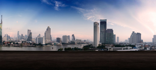 Paranamic view of Bangkok urban cityscape skyline night scene with empty loft cement floor on front.