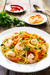 Pasta with prawns and vegetables on wooden background