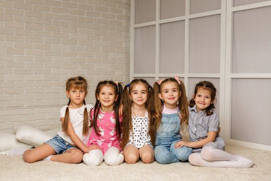Group of kid sitting on floor together. four little girls have fun . friendship concept