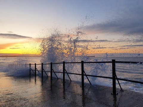 sunrise over pier with splashing wave tramore ireland