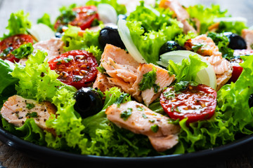 Salmon salad - roasted salmon and vegetables on wooden background