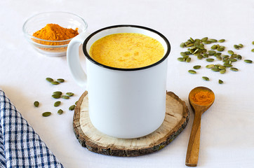 Healthy golden milk with turmeric and honey on white background and tissue. Diet, vegan and detox hot drink. Trendy drink. Copy space. Flat lay.