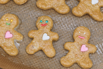 Cinnamon gingerbread men with happy smile and candy hearts with raw transparent glaze on baking paper. Making homemade cookies (still not baked dough). Sweet christmas rustic style recipe