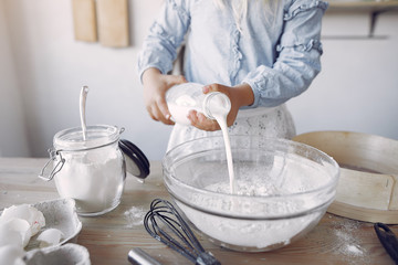 Child in a kitchen. Little girl with a dough. Kid in a blue shirt and white shef hat