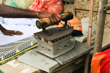 Unidentified senior men ironing clothes with an old coal heated iron in India
