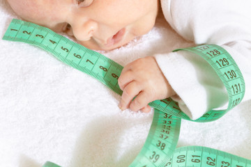 Cute baby infant boy hold with little tiny green centimeter on foreground