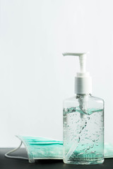 Bottle of hand sanitizer, hand disinfecting gel and surgical mask on white background, crucial for coronavirus prevention through antibacterial hygiene