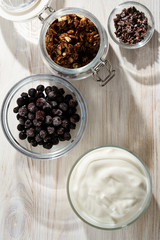 Yogurt parfait ingredients on white rustic table. Hard light, high resolution