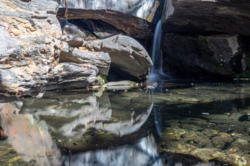Pequeña cascada y reflejo de rocas en el agua