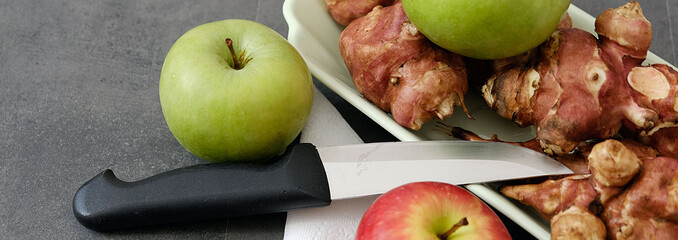 a plate full of Jerusalem artichoke and a green and red apple knife next to it,