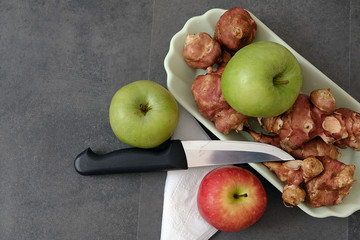 a plate full of Jerusalem artichoke and a green and red apple knife next to it,