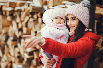 Cute family have fun in a winter park. Woman in a red jacket.