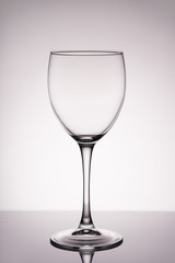 Vertical full size photo of clean transparent with glares wine glass isolated on gray white background with gradient