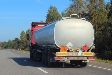 Oil transportation, silver gray fuel tank truck on road at Sunny summer day on blue sky background,...