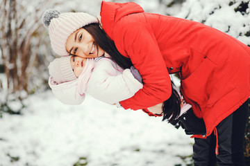 Cute family have fun in a winter park. Woman in a red jacket.