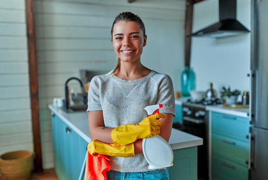 Cleaning concept. An attractive woman in casual clothes and protective gloves with a rag and spray in her hands is about to do general cleaning in the kitchen.
