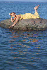 beautiful girl on a stone in the sea