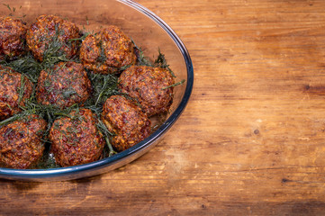 Healthy homemade food on a wooden background. Meat cutlets with dill on a transparent dish close-up