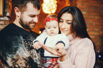 Elegan family standing at home. Beautiful brunette in a pink sweater. Little girl with parents