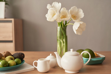 Beautiful tea service on wooden table. Home interior decor, bouquet of flowers in vase, table with set of teapot. Good morning concept. English breakfast. Breakfast at hotel room. Copy space