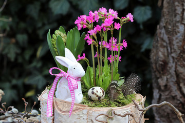 Osterdekoration mit Osterhasen, Rosenprimel und Hyazinthe im Korb