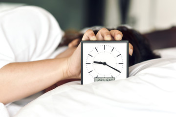 Sleepy girl's hand showing alarm clock and waking up late in the morning, Woman sleep in and laying...