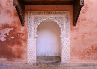 Delicate carved white archway against pink building