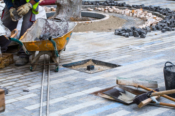 Construction work on pavement. Installation of concrete paver blocks on the sidewalk. The worker...