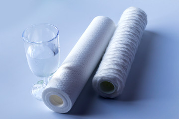 Water filter two units. Near a glass of clean water. White background, no isolation. Close-up.