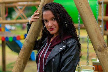 Colombian woman enjoying a sunny afternoon in the city park playing on the swing