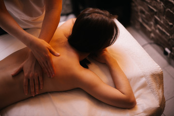 Obraz na płótnie Canvas Close-up female massage therapist does back massage to young woman in massage room with soft lighting. Concept of luxury professional massage. Concept of body care.