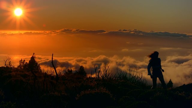 young girl travels in the clouds of her dreams in over with clouds on top of a mountain golden sunset at Parque Nacional del Teide National Park tourism in Tenerife Canary islands Shot URSA 4.6K