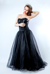 Fototapeta na wymiar young lady posing in fashion long black dress. Portrait of a stunning young woman posing in little black dress
