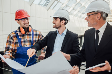 Portrait of two architects and foreman discussing the design of the project.
