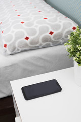 smartphone on bedside table with bed in the background