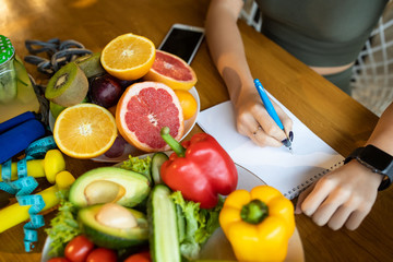 Fresh healthy green vegetables and fruits on wooden table, dietologist write dieting, fitness and active healthy lifestyles concept