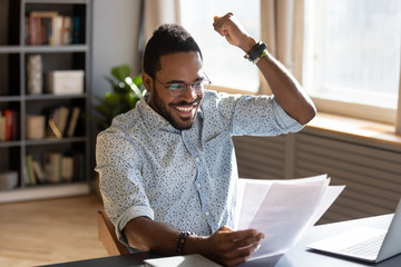 Overjoyed young mixed race businessman celebrating good offer contract.