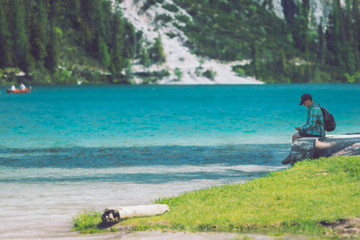 man sitting at beach of mountains lake enjoying the view